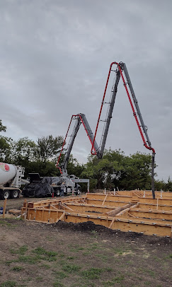 Concrete pump truck pouring a residential foundation at dusk